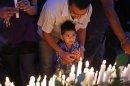 A boy prays with his father after lighting a candle during a memorial service in front of the Westgate shopping mall in Nairobi