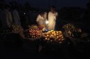 Men buy fruit from a stall that is lit with a gas-lamp during a power outage in Rawalpindi