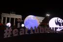 A WWF activist dressed as a panda bear stands next to an illuminated globe in front of the Brandenburger Gate in Berlin during the the global climate change awareness campaign Earth Hour on March 28, 2015