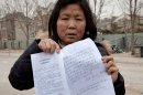 In this Saturday, March 9, 2013 photo, Zhao Meifu, a farmer from Gansu province shows the papers of her labor camp detention in Beijing. Zhao had been seeking redress for decades over a land grab by village officials. Tired of her complaints, police saw the labor camp as a quick way to get rid of her. She was locked up in a long hated and often abused penal system known as labor re-education. Chinese police have used it to lock up tens of thousands of people for up to four years without a trial or a judge's review. Established to punish early critics of the Communist Party, it was retooled to focus on petty criminals but now is used by local officials to deal with people challenging their authority on issues including land rights and corruption. (AP Photo/Andy Wong)
