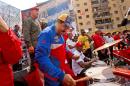 Venezuela's President Nicolas Maduro plays the drums as he arrives for a May Day rally in Caracas, Venezuela, Friday, May 1, 2015. Maduro said at the rally he would raise the minimum wage and pensions for retirees by 30 percent, bringing the minimum wage to around 6,700 bolivars per month. That's about $1,000 at the country's official exchange rate but less than $25 at the black market rate widely used to set many prices. (AP Photo/Fernando Llano)