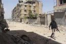 A rebel fighter carries his weapon as he walks along a damaged street in the Mleha suburb of Damascus