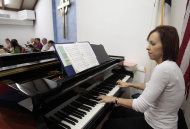 In an Wednesday, Oct. 26, 2011 photo, Michelle Hartman, an elementary school language arts and science teacher, plays the piano at a local Presbyterian church in Plantation, Fla.. The single mother has a master's degree in educational leadership and has been a teacher 15 years. But she says she cannot afford to leave any of her additional jobs. The extra jobs bring in about $6,000 more a year salary on top of her $46,000 a year salary. (AP Photo/Alan Diaz)