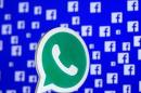 A 3D printed Whatsapp logo is seen in front of a displayed Facebook logo in this illustration taken