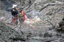 In this photo, published Sunday, March 30, 2014, by the Seattle Times, Randy Fay, a volunteer rescue technician with Snohomish County's SnoHawk 10 rescue helicopter, helps Jetty Dooper, from the Netherlands, after a mudslide struck near Oso, Wash., on Saturday, March 22, 2014. Dooper, while visiting her friend Robin Youngblood who lived in the area, was caught in the slide when a wave of mud crashed into Youngblood's house. (AP Photo/Larry Taylor)