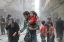 A Syrian man carrying a child makes his way amid rubble following reported air strikes by government forces in the Aleppo district of Ansari, in the southwest of the city, on April 15, 2014