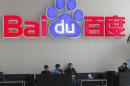 People sit in front of the company logo of Baidu at its headquarters in Beijing