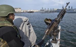 A US Navy sailor mans a gun on the deck of the USS …