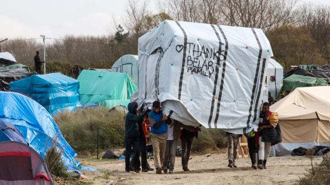 Migrant men move a tent in the &quot;Jungle&quot; refugee camp in Calais on November 12, 2015 to make way for the installation of containers to house people living in the camp