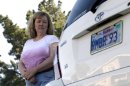 In this April 21, 2012, photo, Candice Hoglan poses for a portrait with her vehicle with a license plate commemorating the events of Sept. 11, 2001, in Sunnyvale, Calif. Hoglan's nephew Mark Bingham was one of the passengers of United Airlines Flight 93, which was hijacked by terrorists on Sept. 11. After the 2001 terrorist attacks, California lawmakers sought a way to channel the patriotic fervor and use it to help victims' families and law enforcement. Their answer: specialty memorial license plates emblazoned with the words, 