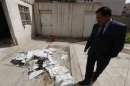 An Iraqi journalist walks past the archive newspapers burned after attack by an armed group at the newspaper's headquarters of Addustour newspaper in Baghdad
