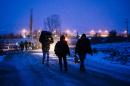 Migrants and refugees walk on a snow covered street after crossing the Macedonian border into Serbia near the village of Miratovac on January 17, 2016
