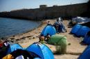 File photo of refugees and migrants sitting next to tents set on the beach next to a medieval fortification wall, at the Souda municipality run camp for refugees and migrants, on the island of Chios