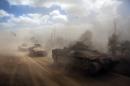 Israeli APCs drive near the Israeli border with Gaza as the come out of the Gaza Strip