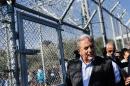 European Migration Commissioner Dimitris Avramopoulos walks by a metal fence at the "Moria" camp, near the port of Mytilene on the Greek island of Lesbos on October 16, 2015