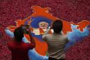 Indians take photographs of a portrait of Bharatiya Janata Party (BJP) leader Narendra Modi, made with colored powder and surrounded by rose petals, at the party office in Gandhinagar, in the western Indian state of Gujarat, Friday, May 16, 2014. Modi will be India's next prime minister, winning the most decisive election victory the country has seen in more than a quarter century and sweeping the long-dominant Congress party from power, partial results showed Friday. (AP Photo/Saurabh Das)