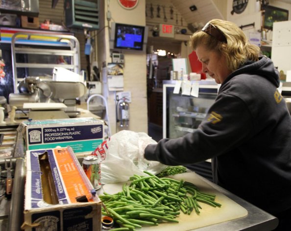 In this photo taken Thursday Dec. 6, 2012, owner of Robie's Country Store and Deli Debbie Chouinard works on cutting up green beans. (AP Photo/Jim Cole)