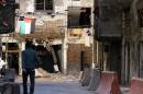 A man walks between bullet riddled buildings at the Yarmuk Palestinian refugee camp in Damascus on June 23, 2014