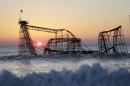 FILE - In a Feb. 25, 2013 file photo, the sun rises in Seaside Heights, N.J., behind the Jet Star Roller Coaster which has been sitting in the ocean after part of the Casino Pier was destroyed during Superstorm Sandy. Work is expected to start Tuesday afternoon, May 14, 2013 to remove the Jet Star coaster from the surf in Seaside Heights. (AP Photo/Mel Evans, File)