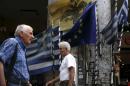 People make their way next to Greek national flags and a European Union flag in Athens