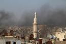 Smoke from burning tyres rises near a minaret of a mosque, which activists said are used to create smoke cover from warplanes, in Aleppo