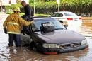 A Los Angeles firefighter helps a driver whose car became stranded on Sunset Boulevard after a 30-inch water main broke and sent water flooding down Sunset and onto the UCLA campus in the Westwood section of Los Angeles Tuesday, July 29, 2014. (AP Photo/Steve Gentry)