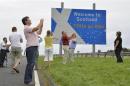 Swiss tourists take photographs next to a road that marks the England - Scotland border, at a layby on the A1 road near Berwick