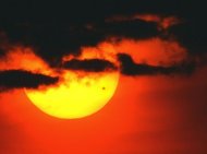 O sol aparece, entre nuvens, enquanto Vênus (o ponto à direita) desponta, em junho de 2004