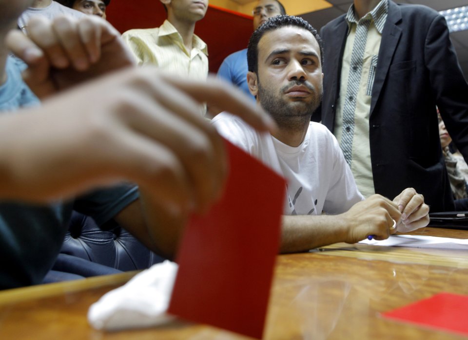 Mahmoud Badr, a leader of the Tamarod, or rebel, movement calling for the ouster of Egypt's president talks as a member holds a red card during a press conference in Cairo, Saturday, June 29, 2013. The youth group leading the campaign against Egypt's president says it has collected the signatures of 22 million Egyptians who want to remove the Islamist leader. Badr said Saturday that 22,134,460 Egyptians have signed the petition demanding President Mohammed Morsi's ouster.(AP Photo/ Amr Nabil)