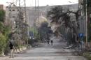 People walk along damaged street in Deir al-Zor, eastern Syria
