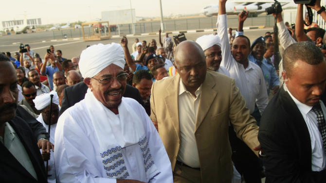 Hundreds of supporters welcome Sudanese President Omar al-Bashir, center left, on his arrival from South Africa as he walks through the crowd at the airport in Khartoum, Sudan, Monday, June 15, 2015. Al-Bashir arrived in Khartoum to cheers of supporters after leaving South Africa, where a court had ordered his arrest based on an international warrant for war crimes charges. (AP Photo/Abd Raouf)