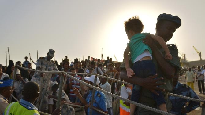 A Djibouti security official carries a young girl down a gangway as people fleeing Yemen arrive aboard a dhow on April 14, 2015 at a the port of Djibouti after crossing the Gulf of Aden