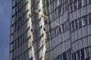 Reflected in a nearby building, Greenpeace protesters climb up The Shard, the tallest building in western Europe, during a protest against the oil company Shell's drilling in the Arctic, Thursday, July 11, 2013. (AP Photo/Sang Tan)
