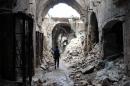 A Syrian rebel walks through a devastated alley of Aleppo's old market on February 27, 2014