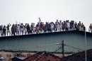 Sri Lankan inmates display guns, throw stones and shout slogans from a roof of a prison in Colombo, Sri Lanka, Friday, Nov. 9, 2012. Sri Lankan security forces engaged in a gunbattle Friday night with rioting prisoners who appeared to have briefly taken control of at least part of a prison in Colombo. Officials said at least 13 people were wounded in the violence with several fatalities. (AP Photo/Gemunu Amarasinghe)