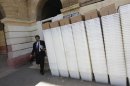 A man walks past rows of election ballot boxes, before they are transported to polling offices, in the premises of the district city court in Karachi