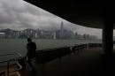 A man takes a photo at a waterfront facing the island skyline as Typhoon Haima approaches in Hong Kong