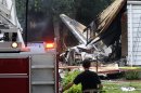 A firefighter surveys the scene of a small plane crash, Friday, Aug. 9, 2013, in East Haven, Conn. The multi-engine, propeller-driven plane plunged into a working-class suburban neighborhood near Tweed New Haven Airport, on Friday. (AP Photo/Fred Beckham)