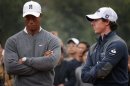 Woods of the U.S. reacts as he stands next to fellow golfer McIlroy of Northern Ireland during trophy presentation after their exhibition event at Jinsha Lake Golf Club in Zhengzhou