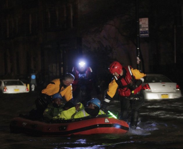 FDNY fire and rescue personnel lead a boat of ConEd power workers through flood waters after their power station was over fun by flood waters in New York