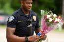 Baton Rouge Police Department Officer Markell Morris holds a bouquet of flowers and a Superman action figure that a citizen left at the Our Lady of the Lake Hospital where the police officers were brought this morning, Sunday, July 17, 2016. Multiple law enforcement officers were killed and wounded Sunday morning in a shooting near a gas station in Baton Rouge. (Henrietta Wildsmith/The Times via AP)
