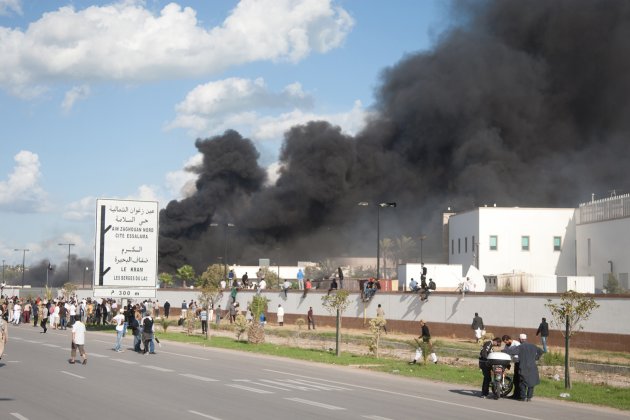 A pall of smoke rises above protesters after they set alight cars in the U.S. embassy parking lot in Tunis, Friday, Sept. 14, 2012. some thousands of demonstrators massed outside the embassy and several were seen climbing the outer wall of the embassy grounds, an Associated Press reporter on the scene said. (AP Photo/Amine Landoulsi)