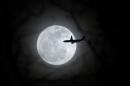 A plane passes in front of a full moon over New York City