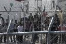 Migrants stand behind a fence at a detention centre for illegal immigrants in Amygdaleza, near Athens, on February 21, 2015