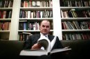 Tokaca poses with one of the four hardback volumes of The Bosnian Book of the Dead in his library in Sarajevo