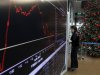 A woman stands next to an electronic board at the reception hall of the Athens stock exchange