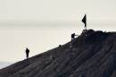 Alleged Islamic State group militants stand next to a black IS flag atop a hill in at the eastern part of the Syrian town of Ain al-Arab, known as Kobane by the Kurds, on October 7, 2014