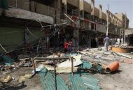 Residents stand amid debris and twisted metal near shops damaged by a car bomb attack that occurred late on Monday in east of Baghdad July 24, 2012. REUTERS/HAYDER KHADIM