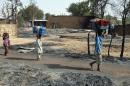 Children fleeing from Boko Haram Islamists walk past burnt houses in Mairi village on the outskirts of Maiduguri, capital of northeast Borno State, on February 6, 2016