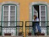 A woman watches a demonstration against government policies from her balcony in Lisbon